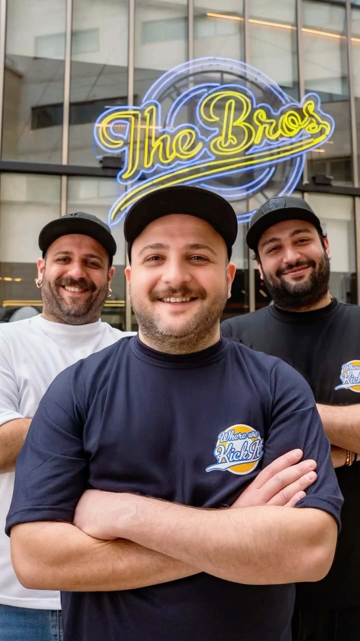 The Bros founders in front of the neon sign