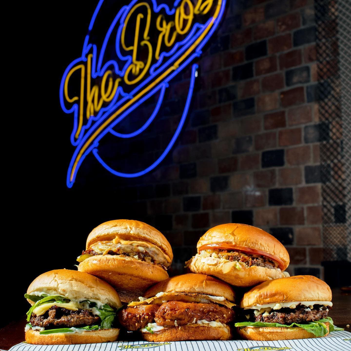 Stack of burgers under The Bros neon sign
