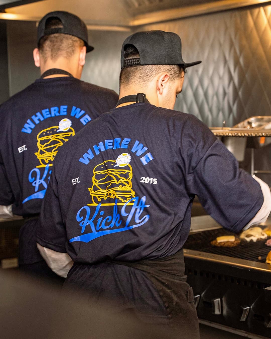 Team at the grill wearing Where We Kick It shirts